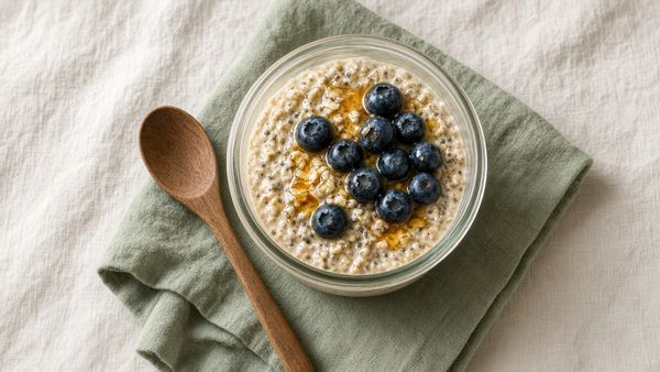 Glass bowl of oats with blueberries and honey on a sage napkin