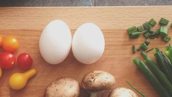 Eggs, mushrooms, cherry tomatoes, and scallions on a wooden board