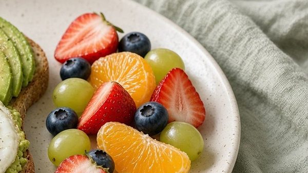 A plate of strawberries, orange segments, blueberries, and grapes