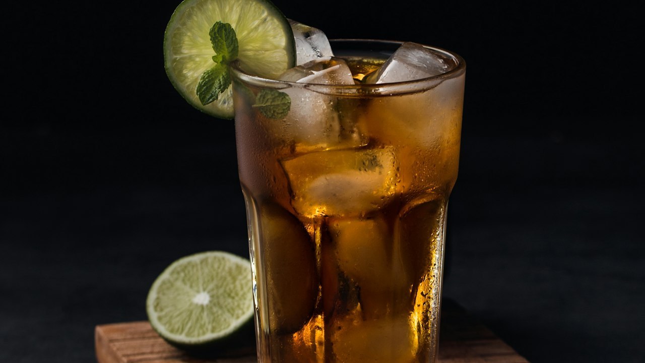 A glass of iced tea with lime on a dark table